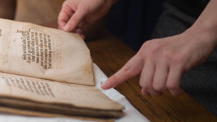 Student handles age-worn book in the Coates Library Special Collections and Archives.