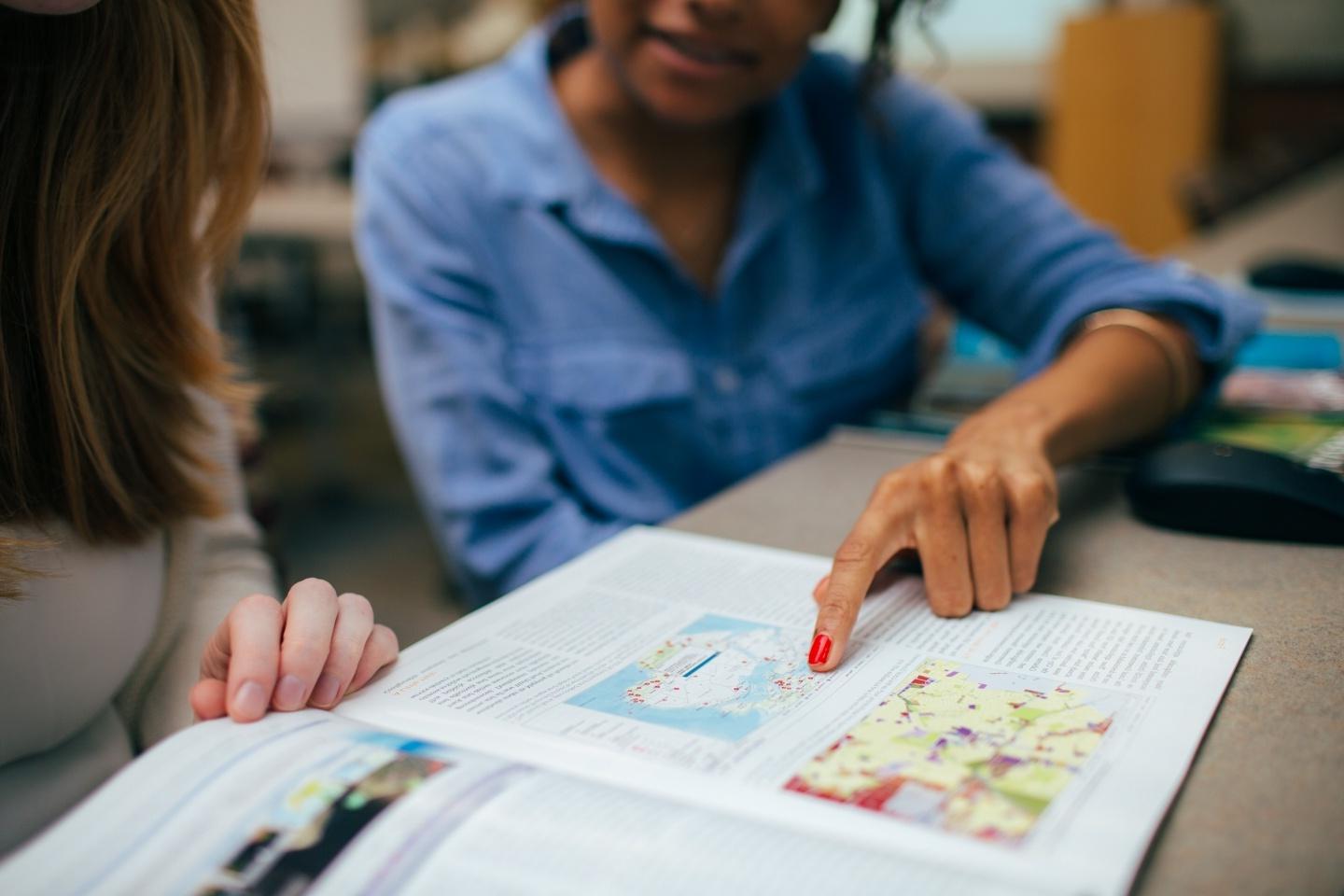 Student pointing at map in a magazine 