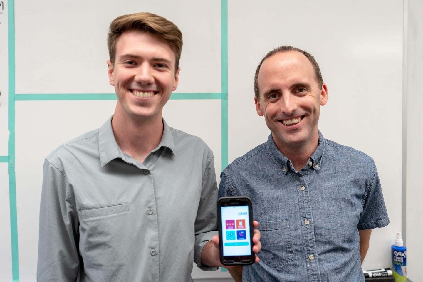 two men smiling and showing an iPhone screen