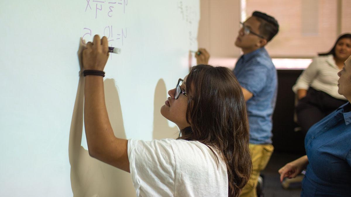 Upward Bound students Karla Chavez and Victor Casillas writing math on a board.